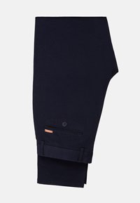 Granatowe spodnie wykonane z bawełny. Posiadają boczną kieszeń z guzikiem i małą metkę z logo marki. Rękawy są starannie zawinięte.