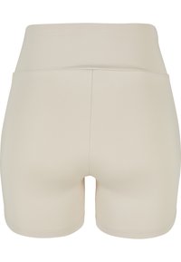 Pantaloncini sportivi beige da donna a vita alta con una fascia larga in vita, mostrati da dietro su sfondo bianco.