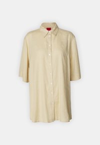 Camicia di lino gialla chiara con maniche corte, colletto a punta e chiusura frontale con bottoni. Presenta bottoni bianchi e una vestibilità rilassata.