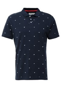 Polo bleu marine en coton, présentant un motif de petites formes blanches et un accent rouge à l'intérieur du col. Patte de boutonnage à deux boutons.