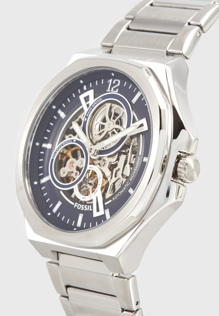 Silver stainless steel watch with a black dial, skeleton design, visible movement, and a polished link bracelet. Features large hour markers and crown.
