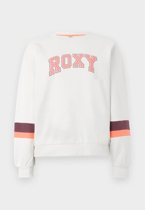Biela mikina s nápisom "ROXY" v ružovom texte. Má fialové a oranžové pruhy na rukávoch. Mäkký materiál, s dizajnom okrúhleho výstrihu.
