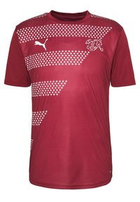 Punainen urheiluondero smooth-kankaasta, jossa on valkoisia ristikkäismalleja ja Puma-logo vasemmassa rintataskussa. Lyhyet hihat ja pyöreä kaula-aukko.