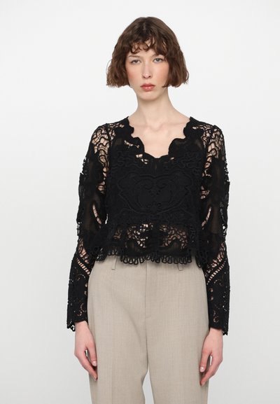 Sort bluse i blonde med scalloped udskæring, lange ærmer og intrikate blomster mønstre. Korte design med frynse detaljer ved kanten.