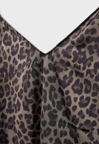 Tissu marron avec un motif léopard noir, présentant un décolleté en V et un détail de couture centrale.