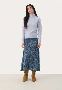 Light blue turtleneck sweater with long sleeves, paired with a blue floral-patterned maxi skirt and tan suede knee-high boots.