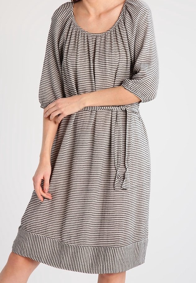 Femme portant une robe longueur genou avec des rayures horizontales noires et blanches, manches 3/4, encolure froncée et ceinture nouée à la taille.