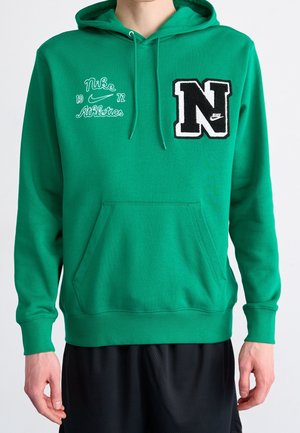 Groene Nike hoodie met voorzak, zwart-witte "N" patch op de rechterborst en "Nike Athletics 1972" tekst met swoosh op de linkerborst.