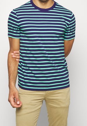 T-shirt w paski w kolorze granatowym i miętowym, z okrągłym dekoltem i krótkimi rękawami, wykonany z miękkiego materiału, połączony z beżowymi spodniami.