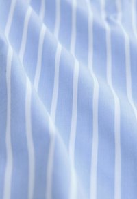 Light blue fabric with narrow white stripes, smooth texture, slightly wrinkled appearance, focusing on the soft, woven design.