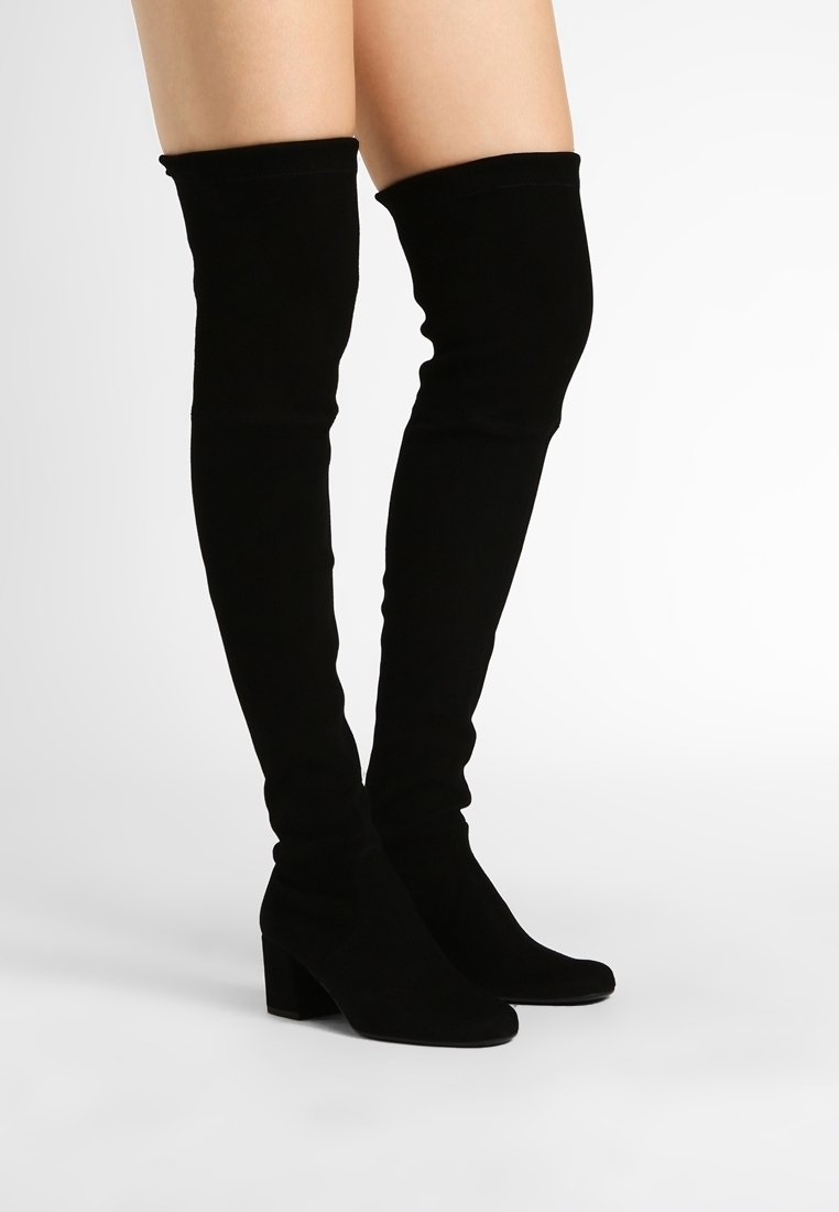 Bottes montantes en daim noir avec talon bloc. Texture lisse, design ajusté et hauteur jusqu'au genou. Silhouette simple et élégante.