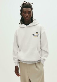 Grauer Hoodie mit einer Fronttasche und gerippten Bündchen, mit "Mickey's Coffee" in Blau und Gelb gestickt. Glatte Textur aus Baumwollmischung.