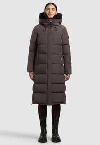 Manteau matelassé gris foncé avec un col haut, doté d'une capuche amovible, de poches avant et d'une fermeture éclair. Tissu texturé et chaud.