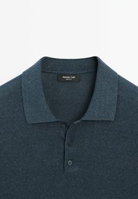 Tmavě modré polo tričko s límečkem, třemi knoflíky a texturovanou látkou. Na štítku je nápis "Massimo Dutti."