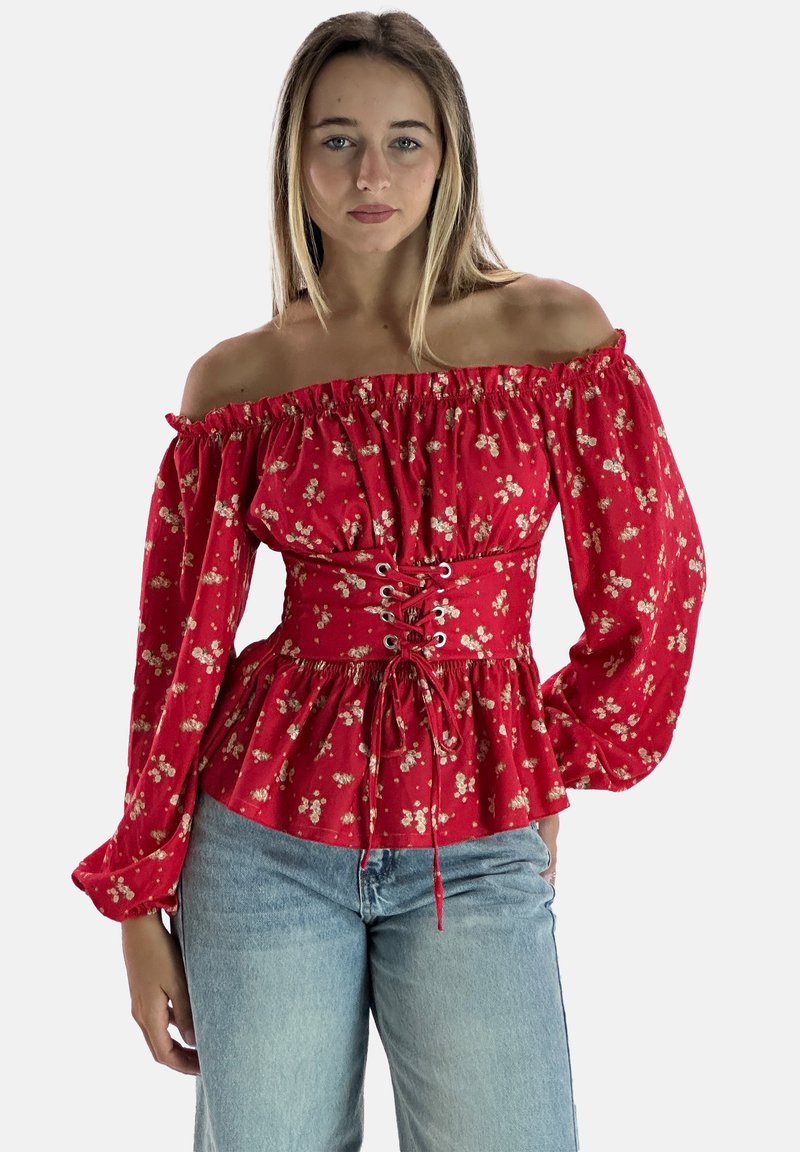 Blusa rossa scollata sulle spalle con maniche a palloncino lunghe, motivo floreale, scollatura arricciata e vita aderente con dettagli in pizzo. Abbinata a jeans blu.