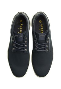 Scarpe di tela navy con suole bianche, dotate di punta arrotondata, design con lacci, dettagli grigi sul colletto e marchio "REDSKINS 1984".