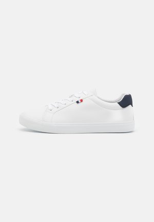 White leather sneakers with a smooth surface and rounded toe. Features flat laces and a small navy accent on the heel. Rubber sole.