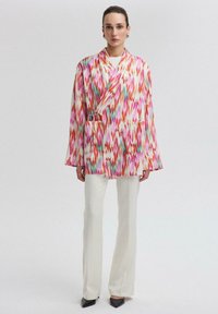 Světlý, vzorovaný dlouhý kimono kabát v odstínech růžové, oranžové a zelené. Vyrobeno z lehké tkaniny, se dvěma předními kapsami a šněrováním.