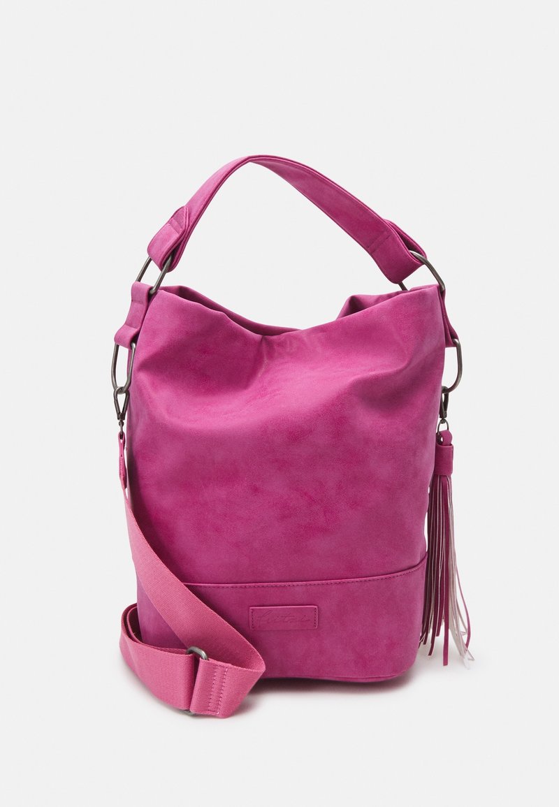 Różowa zamszowa torebka kubełkowa z szerokim paskiem na ramię, odczepianym paskiem na ramię oraz długim detalem z frędzlem na białym tle.