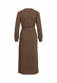 Brązowa sukienka z długim rękawem o prążkowanej fakturze i paskiem w talii. Posiada okrągły dekolt i sięga do ziemi.