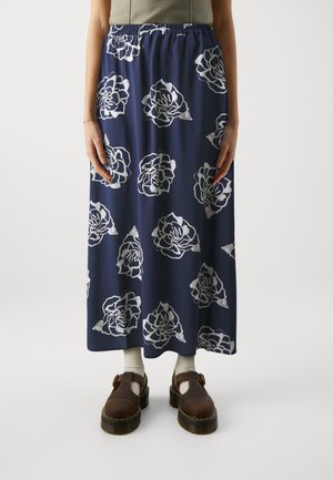 Navy blue maxi-hame valkoisella kukkakuviolla, joustava vyötärö, kevyttä kangasta ja hulmuava muotoilu. Yhdistetty ruskeisiin kenkiin ja sukkiin.
