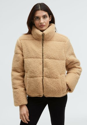 Beige faux fur jacket with a high collar, featuring a front zipper, boxy design, and horizontal quilted pattern. Soft texture and relaxed fit.