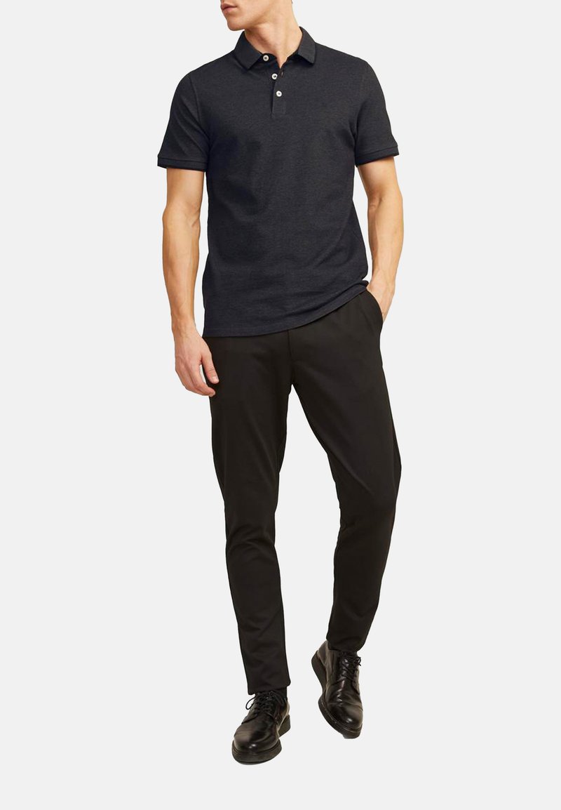 Navy polo shirt med korte ærmer og tre-button placket, parret med sorte slim-fit bukser og sorte snørebåndssko. Glat tekstur, afslappet design.