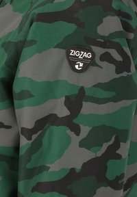 Camouflagejas met groene en grijze patronen, voorzien van een zwart Zigzag-logo op de schouder, gemaakt van duurzaam materiaal.