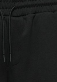 Ceinture en tissu noir avec élastique et cordons noirs, comprenant une poche latérale avec bordure cousue.