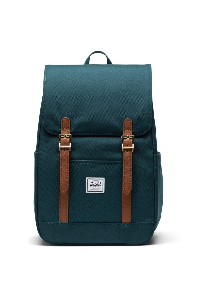 Tealowy plecak z tkaniny z brązowymi skórzanymi paskami i złotymi okuciami. Posiada przednią kieszeń i naszywkę z logo. Solidny, prostokątny kształt.