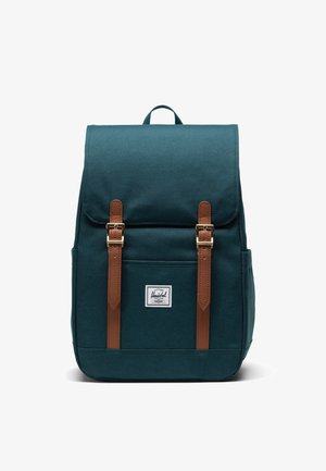 Tyrkysový textilný batoh s hnedými koženými popruhmi a zlatým kováním. Obsahuje predné vrecko a logo nášivku. Pevný, obdĺžnikový dizajn.
