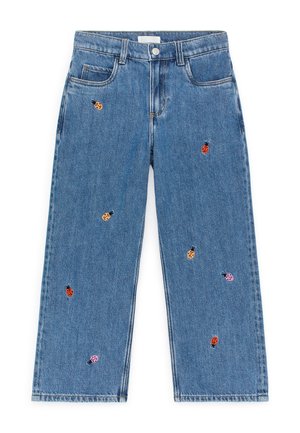 Niebieskie dżinsy jeans o szerokich nogawkach z wyszywanymi, wielobarwnymi biedronkami rozrzuconymi po tkaninie.