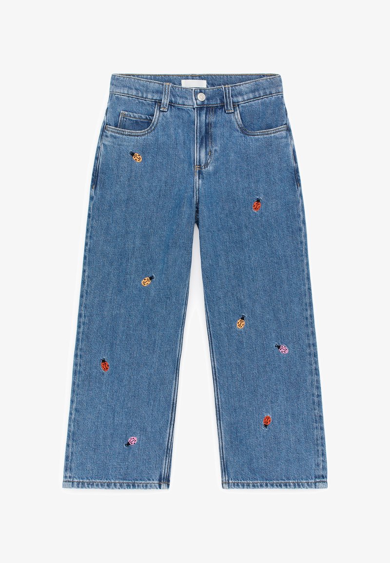 Jean en denim bleu avec jambes larges et coccinelles multicolores brodées réparties sur le tissu.