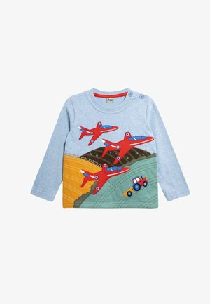 Camisa de manga larga azul claro con apliques de avión rojos y un tractor verde sobre un paisaje multicolor. Botones en el hombro para facilitar el vestir.