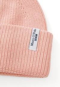 Light pink ribbed knit beanie with a folded cuff featuring a white label reading "Marc O'Polo DENIM" in black text.