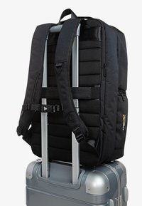 Fekete hátizsák párnázott hálós textúrával, állítható pántokkal, ezüst bőrönd fogantyúra erősítve. Strapabíró hardverrel és Cordura márkázással rendelkezik.