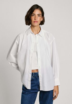 Hvid skjorte med knapper lavet af bomuld, med en afslappet pasform, lange ærmer og klassisk krave, parret med høj talje blå jeans.