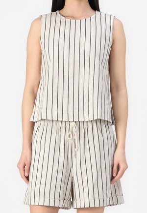 Beżowa bluzka bez rękawów i pasujące szorty z cienkimi pionowymi czarnymi paskami, szorty posiadają ściągacz w pasie i podwinięte krawędzie.