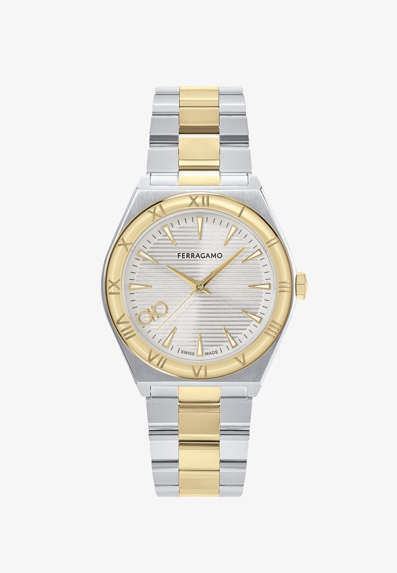 Sudraba un zelta nerūsējošā tērauda pulkstenis ar teksturētu baltu ciparnīcu, romiešu cipariem un datuma displeju pulksten 6. Šveices ražojums.