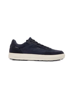 Zapatilla negra de corte bajo con suela blanca, diseño con cordones y etiqueta impermeable en el lateral, mostrada desde el lado exterior.