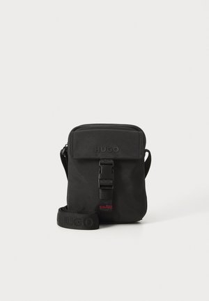 Borsa a tracolla nera realizzata in tessuto resistente. Presenta una chiusura con pattina, una tracolla regolabile con logo impresso e un dettaglio con fibbia anteriore.