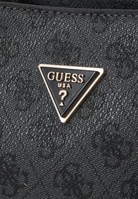 Crni teksturirani materijal s trokutastim zlatnim i crnim Guess USA logom. Ima uzdignuti dizajn i suptilan uzorak u pozadini.