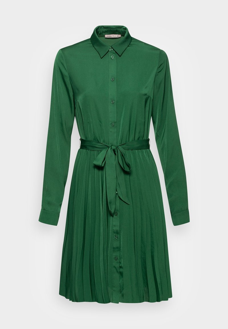Grünes plissiertes Kleid mit langen Ärmeln, durchgehender Knopfleiste und passendem Bindegürtel. Hergestellt aus einem glatten Stoff mit Kragen und verstellbaren Bündchen.