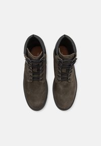 Botine din suede maro, cu accente din piele neagră, vârf rotund și șnururi negre contrastante. Talpă plată cu detaliu de cusătură.