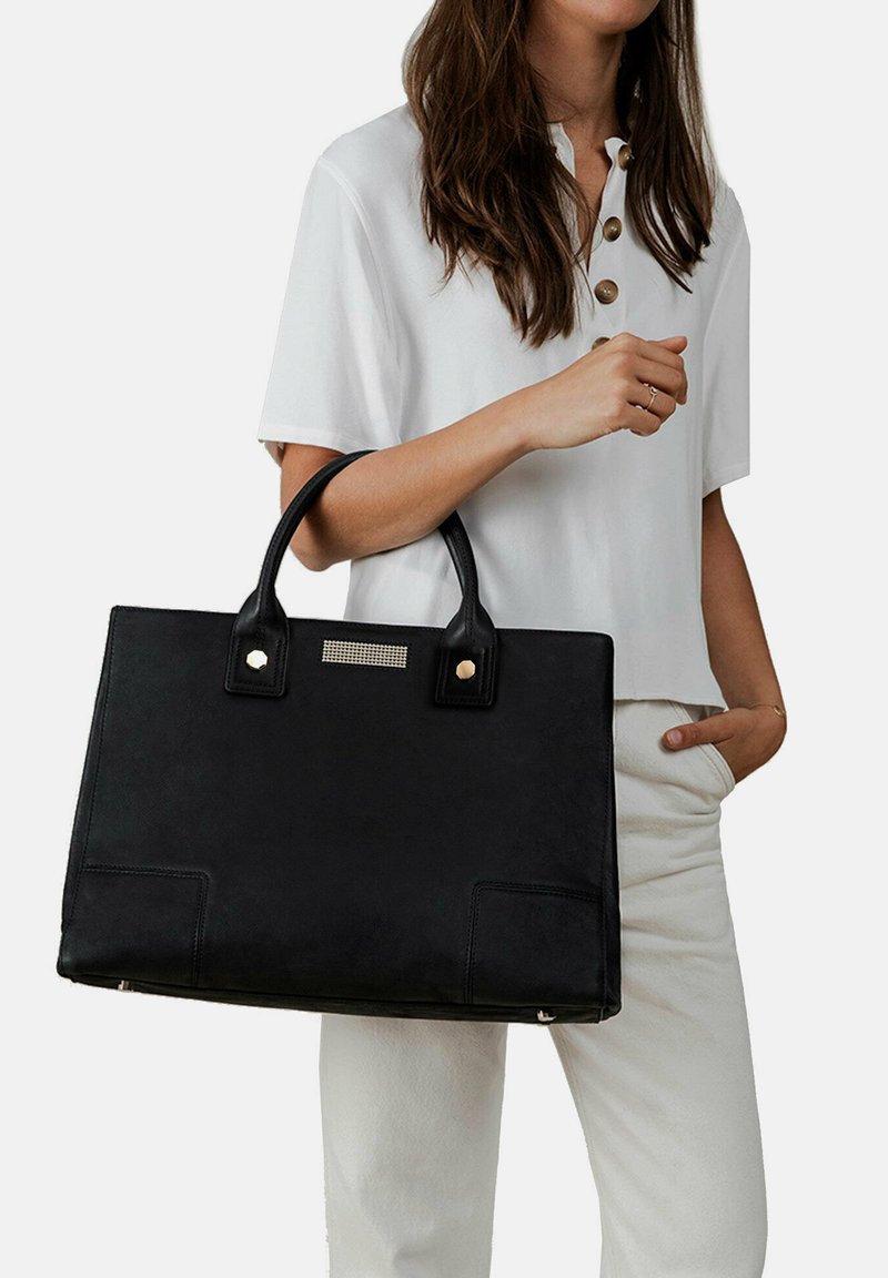 Zwarte leren handtas met dubbele handvatten, een gladde textuur, rechthoekige vorm, met een metallic accent en voorvakken.