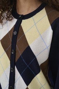 Kardigan, millel on tumesinine, kollane, pruun ja valge rombimuster heleroheliste rõhutustega. Esiküljel nööbid ja sooniline kaelus, kootud tekstuur.