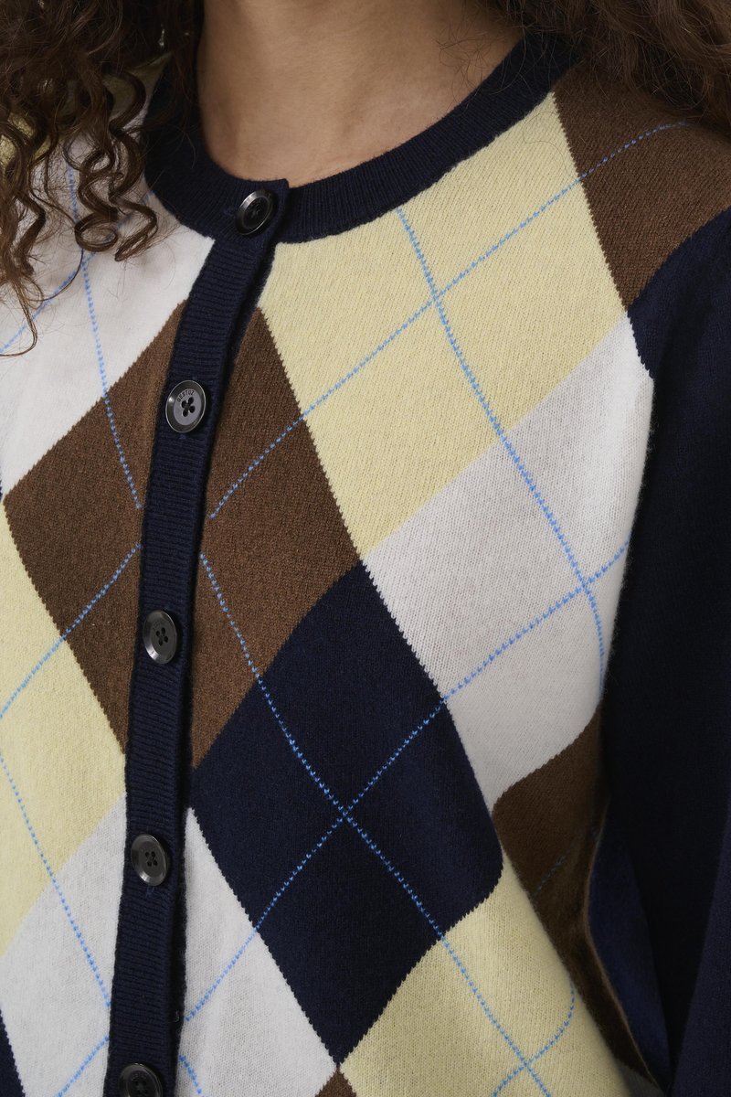 Cardigan avec un motif en losanges bleu marine, jaune, marron et blanc avec des accents bleu clair. Boutons à l'avant et encolure côtelée, texture tricotée.