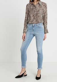 Bluse med leopardprint og knap-up krave, parret med lys blå skinny jeans rullet op i benene og sorte slingback sko.