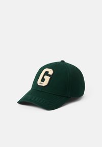 Zelená bejzbalová čiapka z látky, s vyvýšeným krémovým logom "G" vpredu, zakriveným šiltom a prešitím.