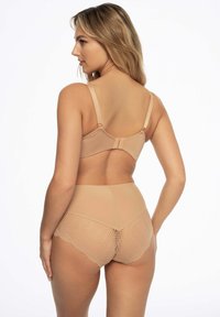Nude biustonosz i majtki z wysokim stanem. Biustonosz ma gładki materiał i regulowane ramiączka. Majtki mają teksturowany wzór w jodełkę oraz falbane brzegi.